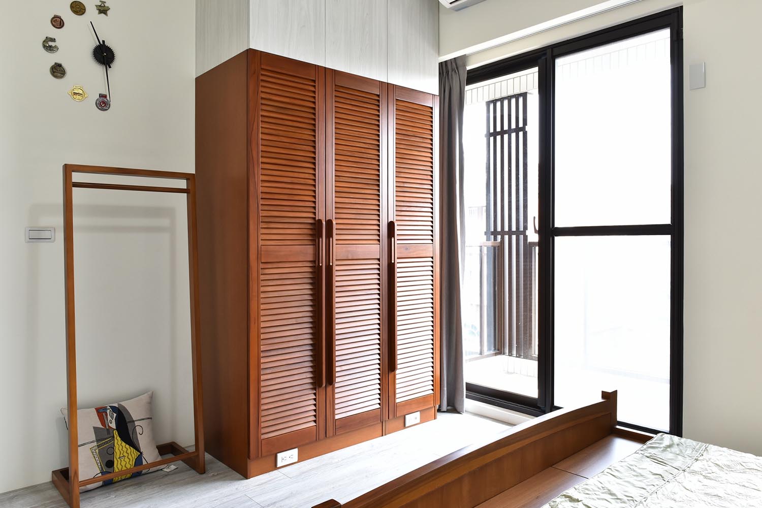 床的對面為實木衣櫃組靠右邊牆，上方使用系統櫃做到頂