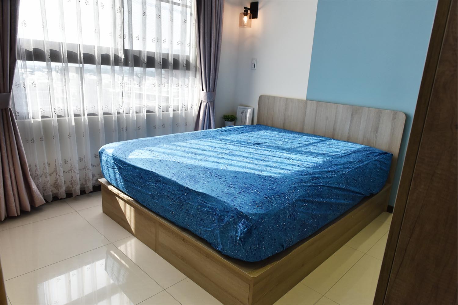 主臥使用系統床假，灰色木質調搭配藍色床包